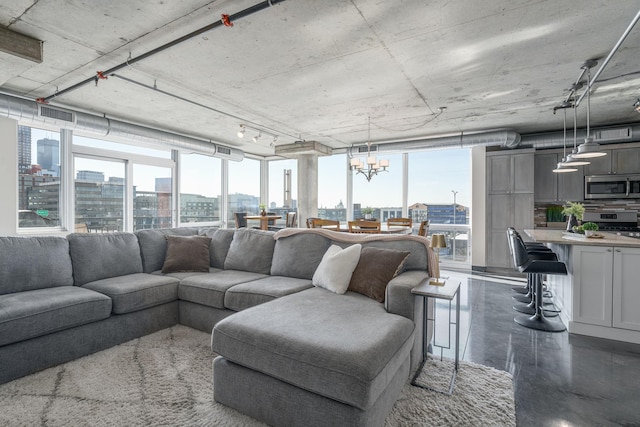 living room with finished concrete flooring, plenty of natural light, a view of city, and a notable chandelier