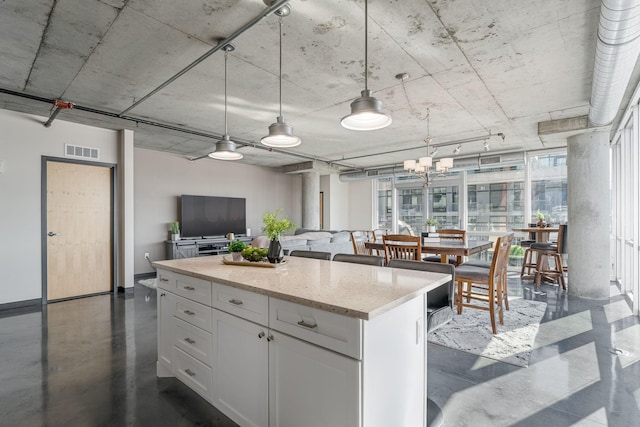 kitchen with visible vents, white cabinets, open floor plan, a center island, and pendant lighting