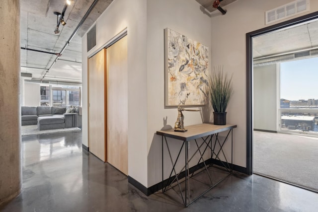 hall with concrete floors, visible vents, and plenty of natural light