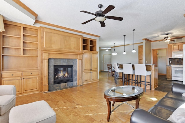 living area featuring crown molding, ceiling fan, a fireplace, wood finished floors, and a textured ceiling