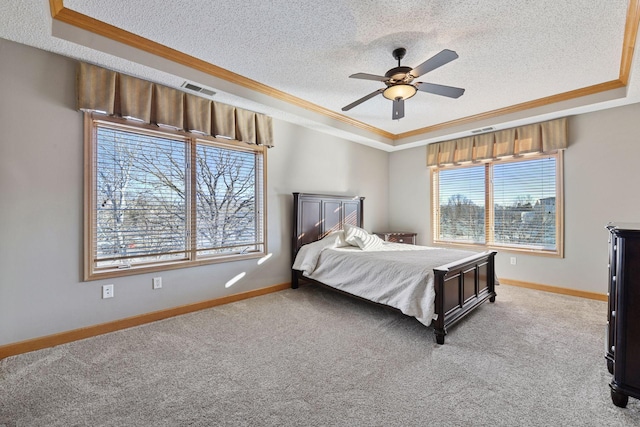 bedroom with a textured ceiling, a tray ceiling, carpet, and ornamental molding