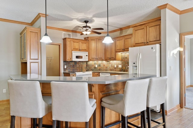 kitchen featuring white appliances, visible vents, a peninsula, a sink, and tasteful backsplash