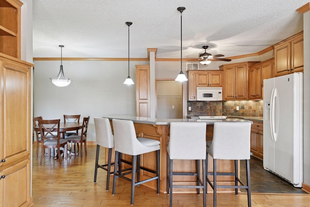 kitchen with white appliances, a kitchen island, decorative backsplash, hardwood / wood-style flooring, and a kitchen breakfast bar