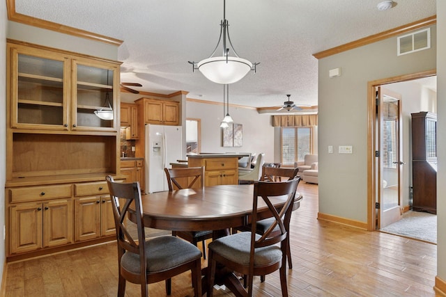 dining area with visible vents, light wood-style flooring, and crown molding