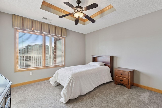 carpeted bedroom with visible vents, a raised ceiling, a ceiling fan, a textured ceiling, and baseboards