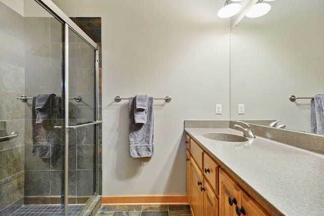 full bathroom with baseboards, vanity, and a shower stall