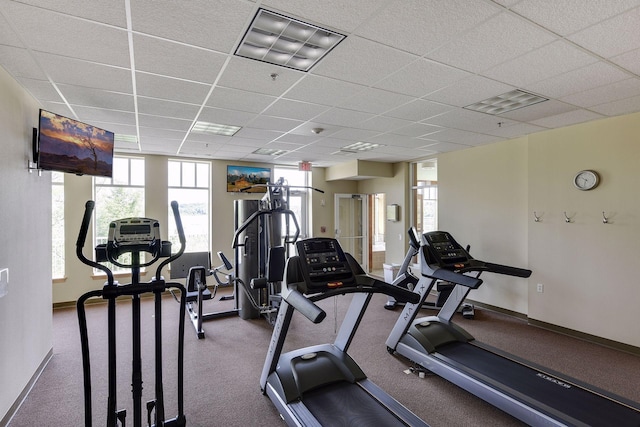 gym with visible vents, a paneled ceiling, and baseboards