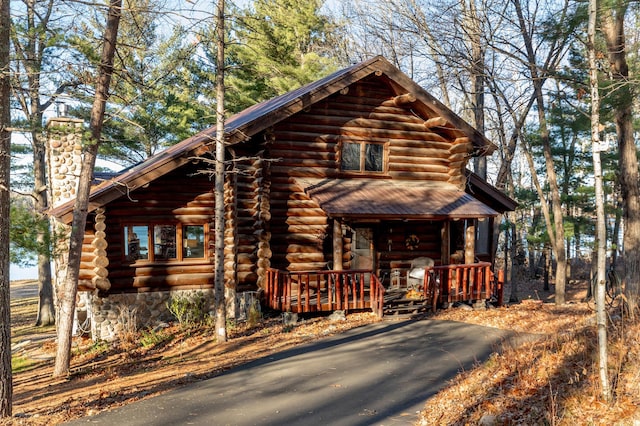 log cabin featuring a porch, log exterior, and a chimney