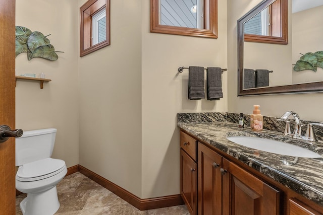 half bath with vanity, toilet, and baseboards