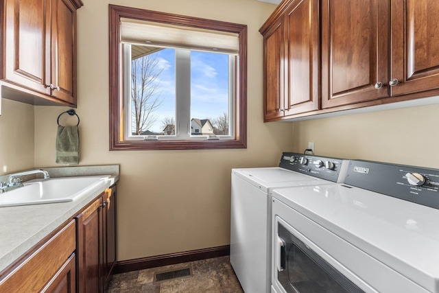 laundry room with visible vents, baseboards, cabinet space, a sink, and washer and clothes dryer