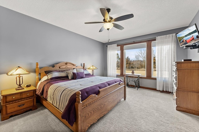 bedroom with baseboards, light carpet, a textured ceiling, and ceiling fan