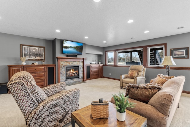 living area featuring baseboards, light carpet, a stone fireplace, recessed lighting, and a textured ceiling