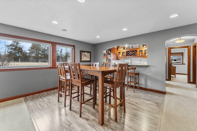 dining room featuring recessed lighting, baseboards, arched walkways, and a textured ceiling