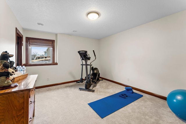 exercise room with carpet, baseboards, and a textured ceiling