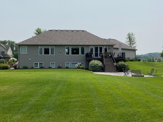 rear view of property with roof with shingles, a wooden deck, an outdoor fire pit, a yard, and stairs