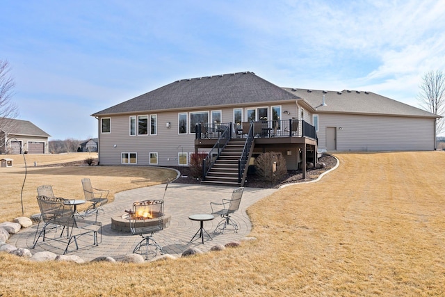 rear view of house featuring stairway, a wooden deck, an outdoor fire pit, a patio area, and a lawn