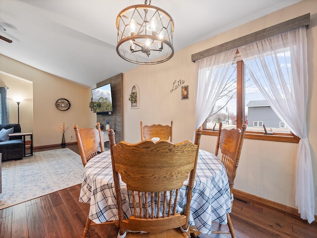 dining room with hardwood / wood-style floors, lofted ceiling, baseboards, and a chandelier