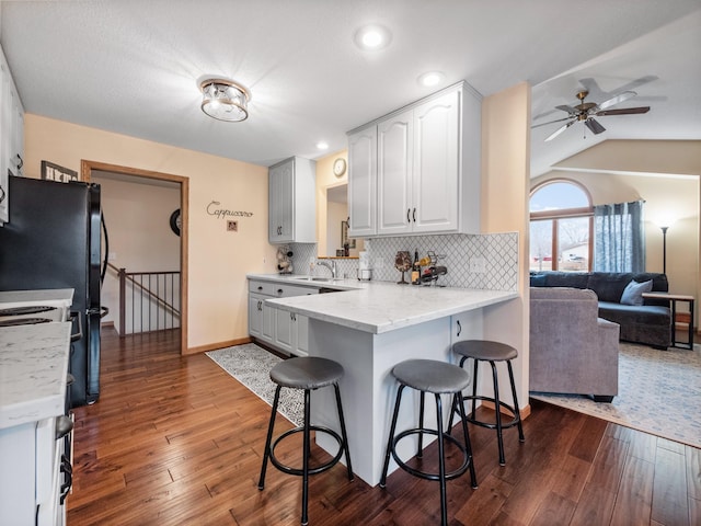 kitchen with dark wood-type flooring, a kitchen breakfast bar, tasteful backsplash, and a sink