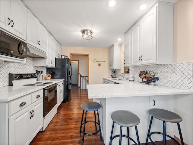 kitchen with under cabinet range hood, range with electric stovetop, white cabinetry, a peninsula, and black microwave