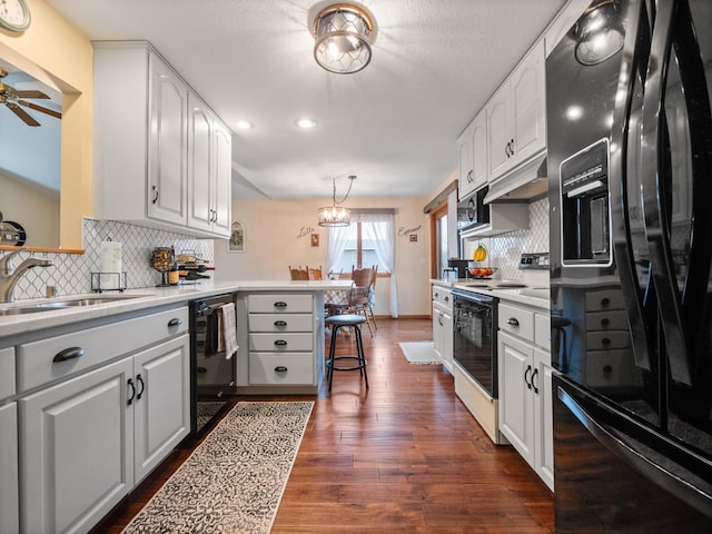 kitchen featuring dark wood finished floors, white cabinets, a peninsula, and black appliances