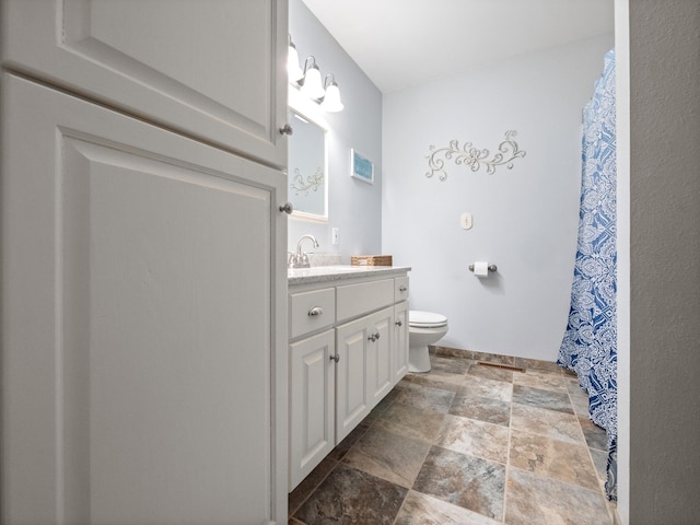 full bath with stone finish floor, toilet, and vanity