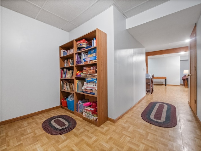 hall featuring a paneled ceiling and baseboards