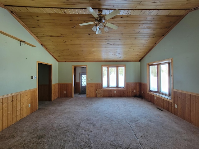 empty room with a wainscoted wall, visible vents, and wood walls