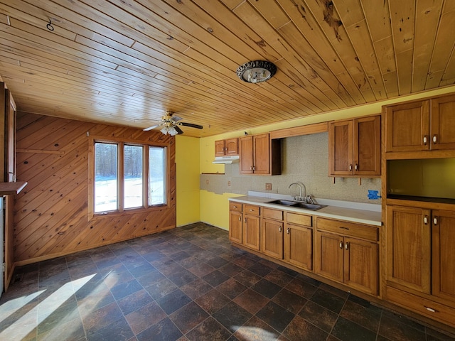 kitchen featuring brown cabinetry, a sink, and under cabinet range hood