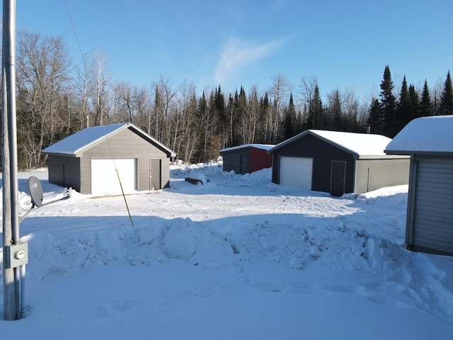 snowy yard with a detached garage and an outdoor structure