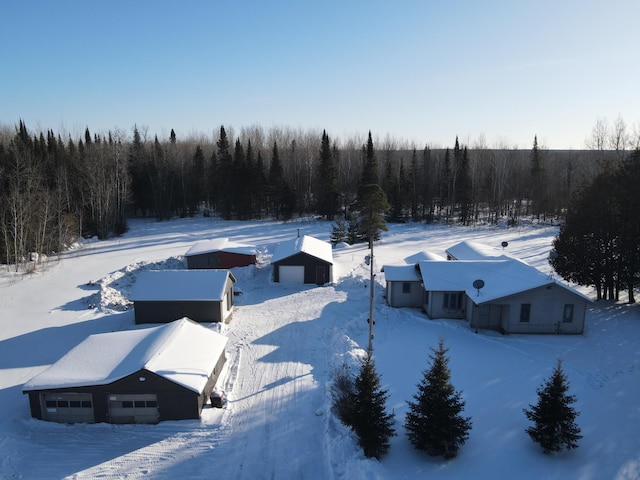 snowy aerial view featuring a wooded view