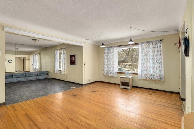 interior space with hardwood / wood-style flooring, baseboards, and a textured ceiling