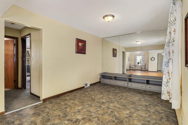 interior space featuring stone finish floor, baseboards, and visible vents