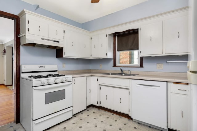 kitchen featuring under cabinet range hood, light floors, light countertops, white appliances, and a sink