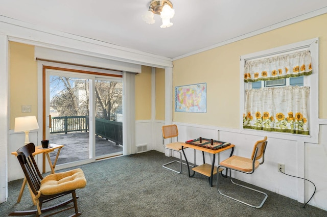 sitting room with visible vents, ornamental molding, carpet flooring, wainscoting, and a decorative wall