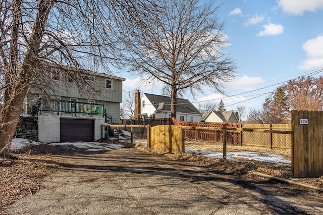 view of yard featuring a fenced front yard, dirt driveway, a garage, and a gate