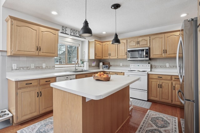 kitchen with light brown cabinets, a kitchen island, light countertops, appliances with stainless steel finishes, and a sink