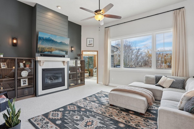 living area with a ceiling fan, baseboards, carpet, and a fireplace