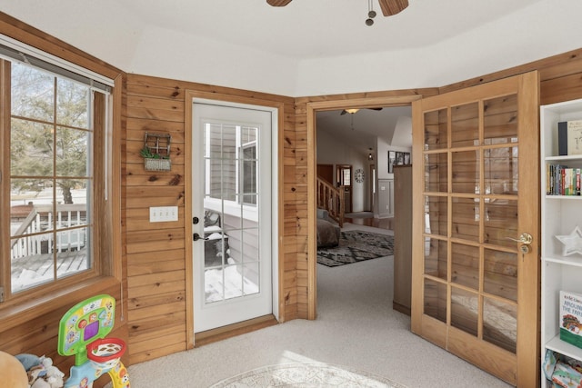 entryway with wooden walls, stairs, ceiling fan, and carpet floors