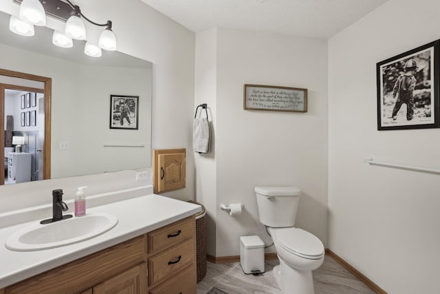 bathroom featuring baseboards, toilet, marble finish floor, and vanity