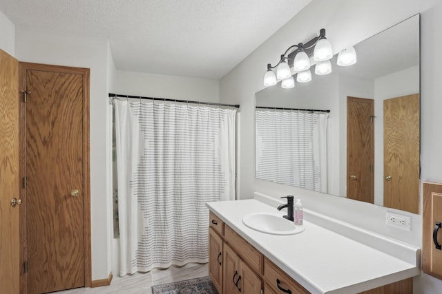 full bath featuring a textured ceiling, vanity, and a shower with shower curtain