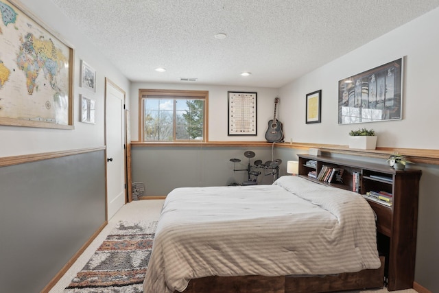 carpeted bedroom with baseboards, visible vents, and a textured ceiling