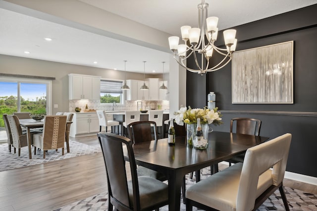 dining space featuring light wood-style flooring, baseboards, a chandelier, and recessed lighting