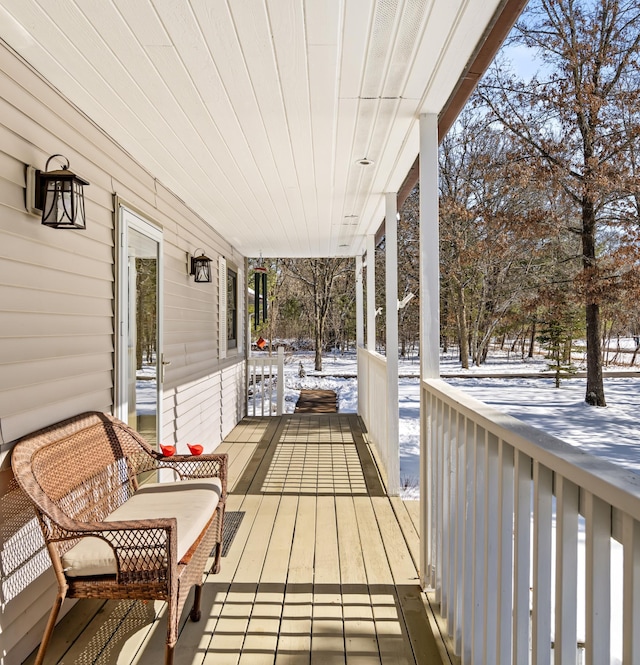 snow covered deck featuring covered porch