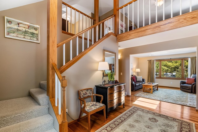 stairs featuring a high ceiling and wood finished floors