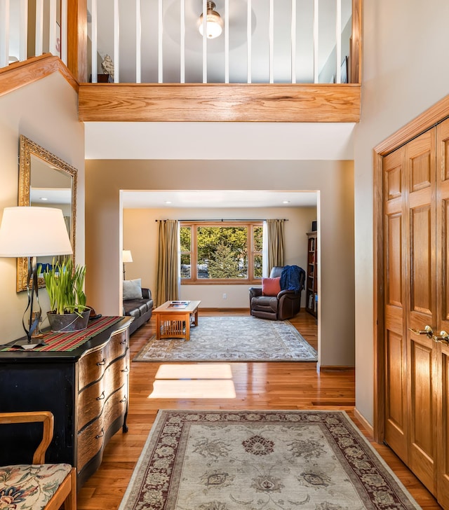 entrance foyer with light wood-type flooring, a towering ceiling, and baseboards