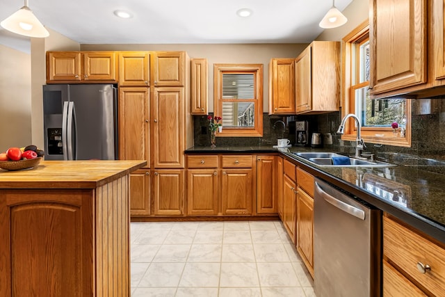 kitchen with appliances with stainless steel finishes, a sink, backsplash, and wooden counters