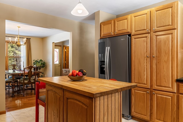 kitchen with stainless steel fridge, wood counters, a kitchen island, and decorative light fixtures