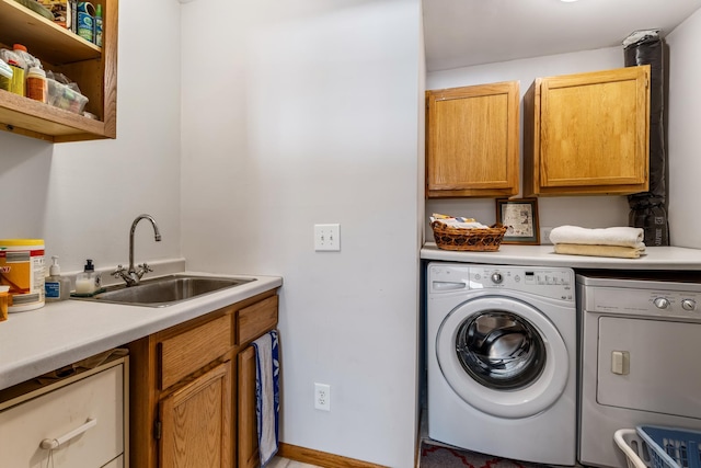 clothes washing area with washer and clothes dryer, a sink, and cabinet space