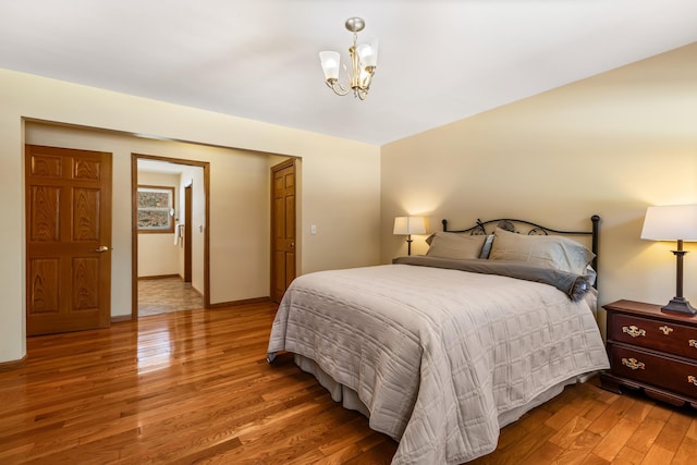 bedroom with light wood-type flooring, baseboards, and a notable chandelier