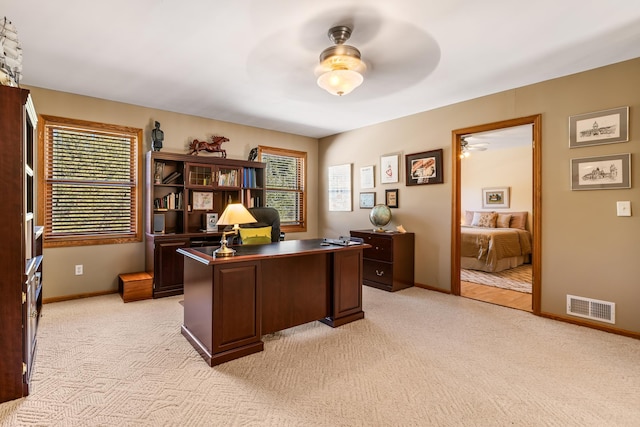 office space featuring ceiling fan, light carpet, plenty of natural light, and visible vents